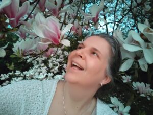 Een witte vrouw staat tussen de takken van een Magnolia.